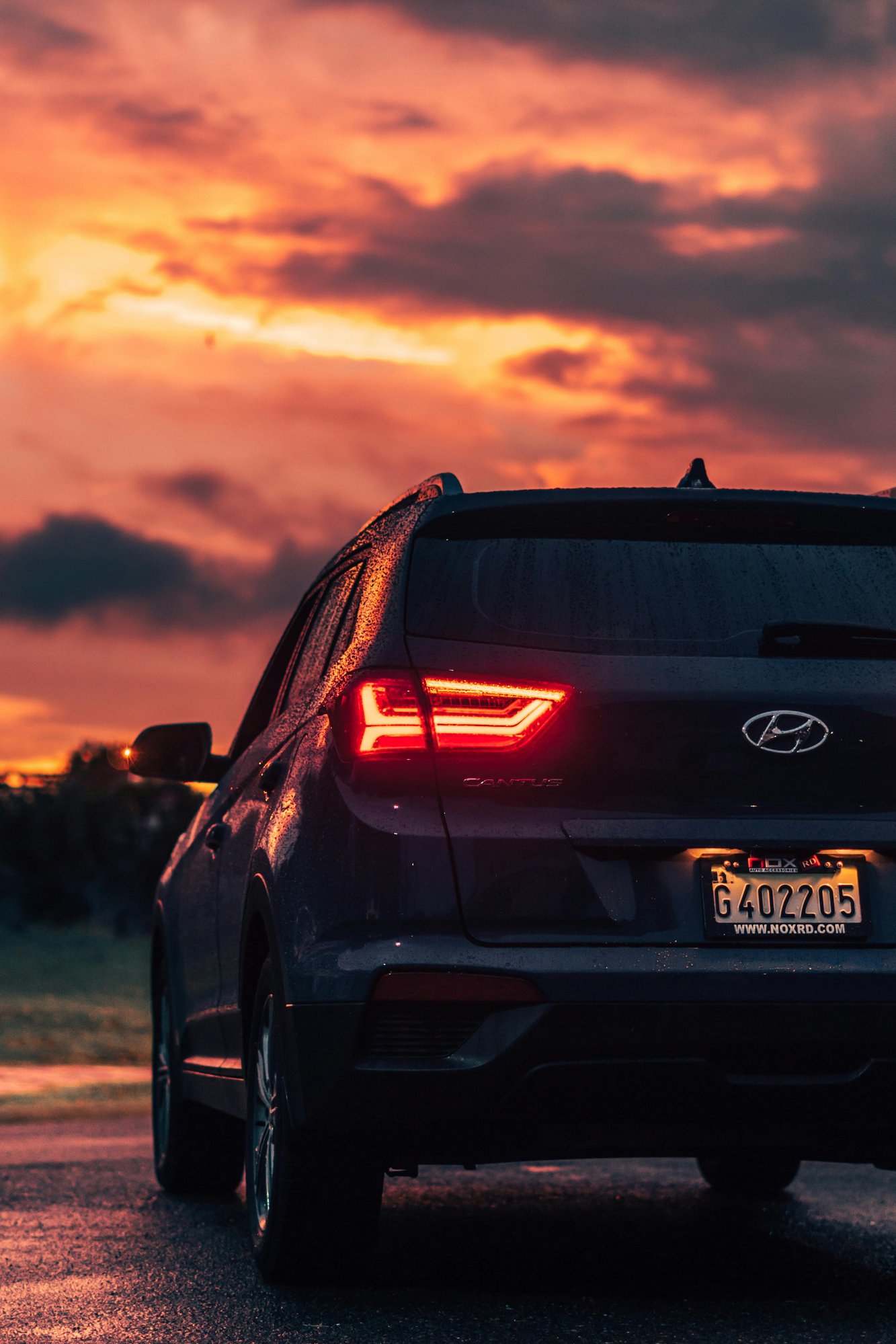 Hyundai crossover parked and watching the sunset, backside view Hyundai crossover parked and watching the sunset, backside view