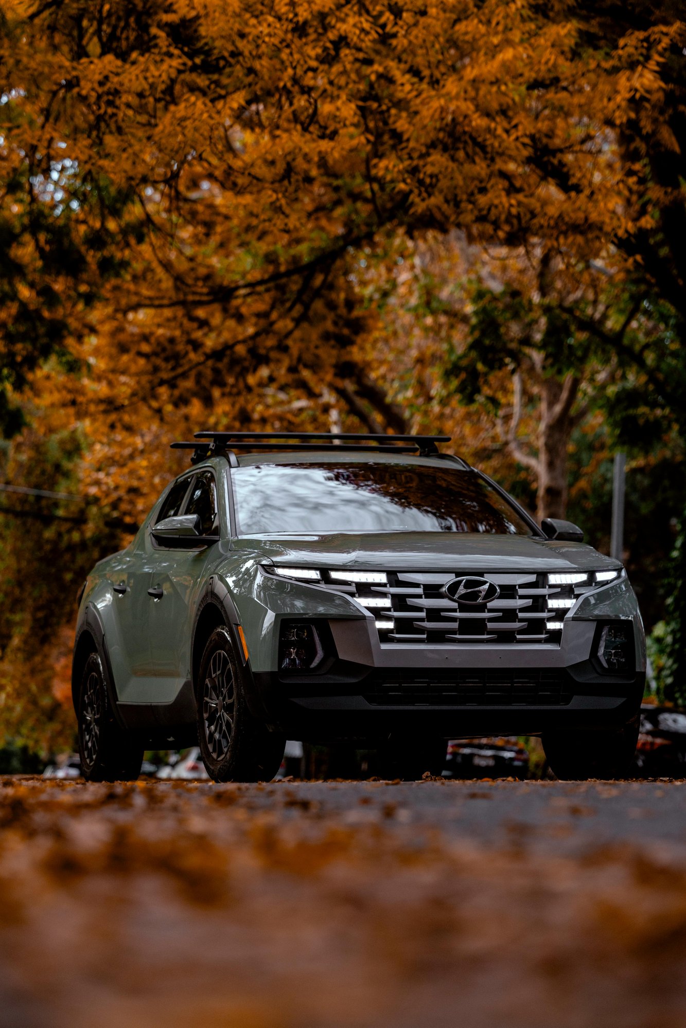 Hyundai SUV drives down the road in autumn, orange leaves have fallen on the ground